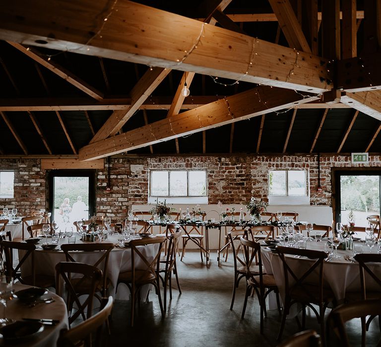 Intimate wedding reception at Woolas Barn with round tables and flower stems in bottle wedding table decor 