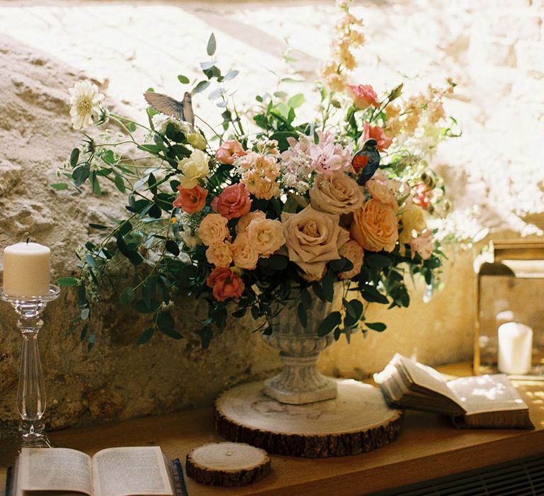 Romantic wedding flower arrangement in an urn with pink, white and green flowers including roses 