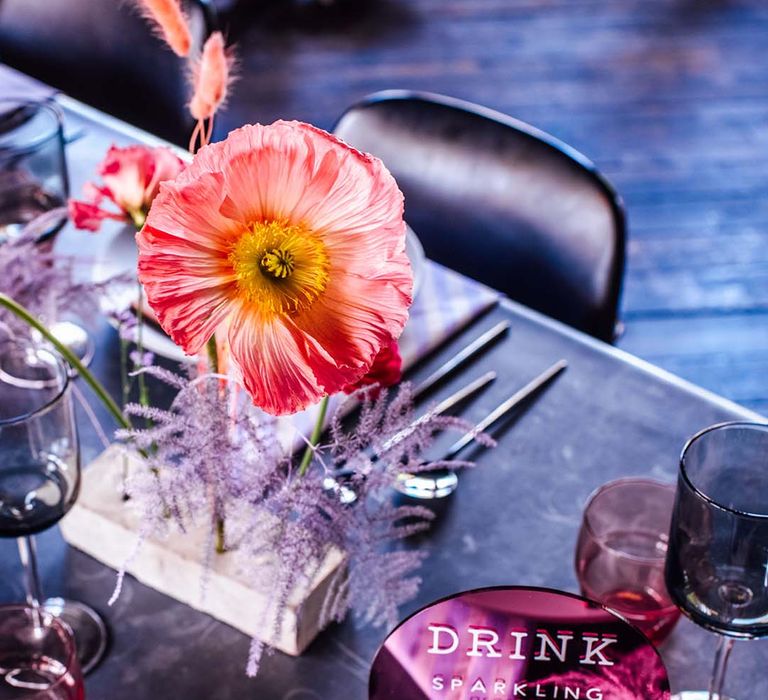 Centrepiece decor with concrete blocks filled with flower stems and an acrylic drinks menu wedding sign 