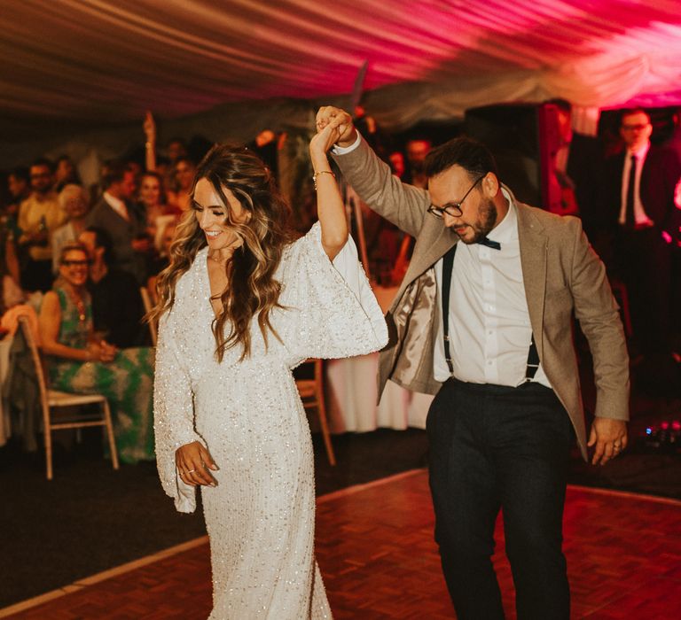 Bride wears batwing reception gown as she dances with her groom on wedding day