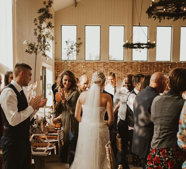 Bride with veil makes entrance into wedding breakfast