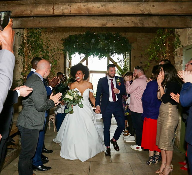 Bride & groom hold hands as they leave wedding ceremony