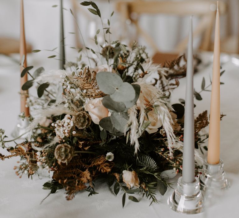 Terracotta and white candles next to floral bouquet