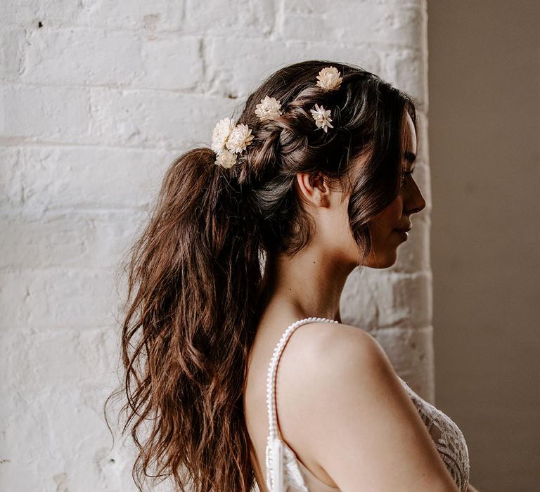 dry flower hair accessories pinned to messy ponytail wedding hairstyle 