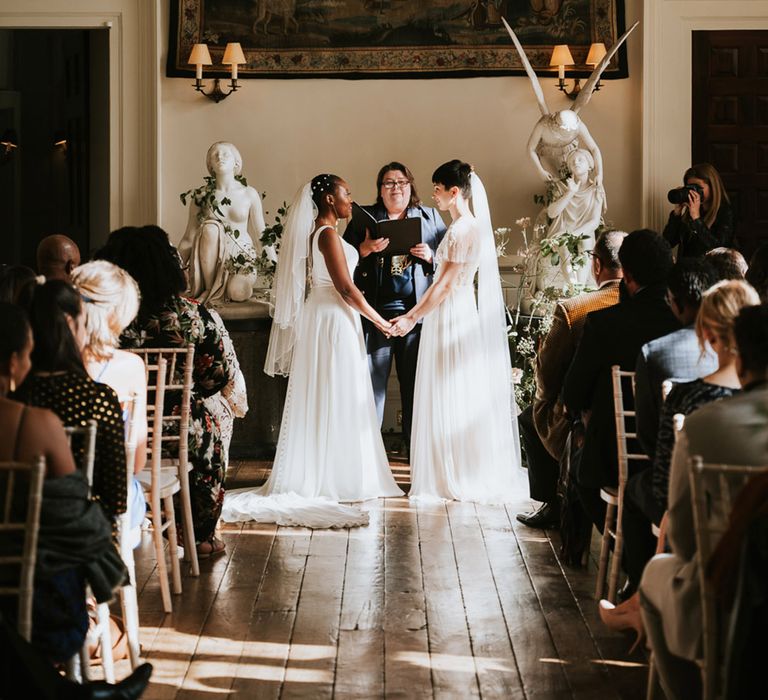 Same-sex civil wedding ceremony at Elmore Court with two brides holding hands exchanging vows 