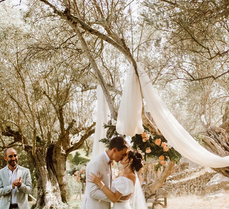 bride in puff sleeve dress shares first kiss with groom 