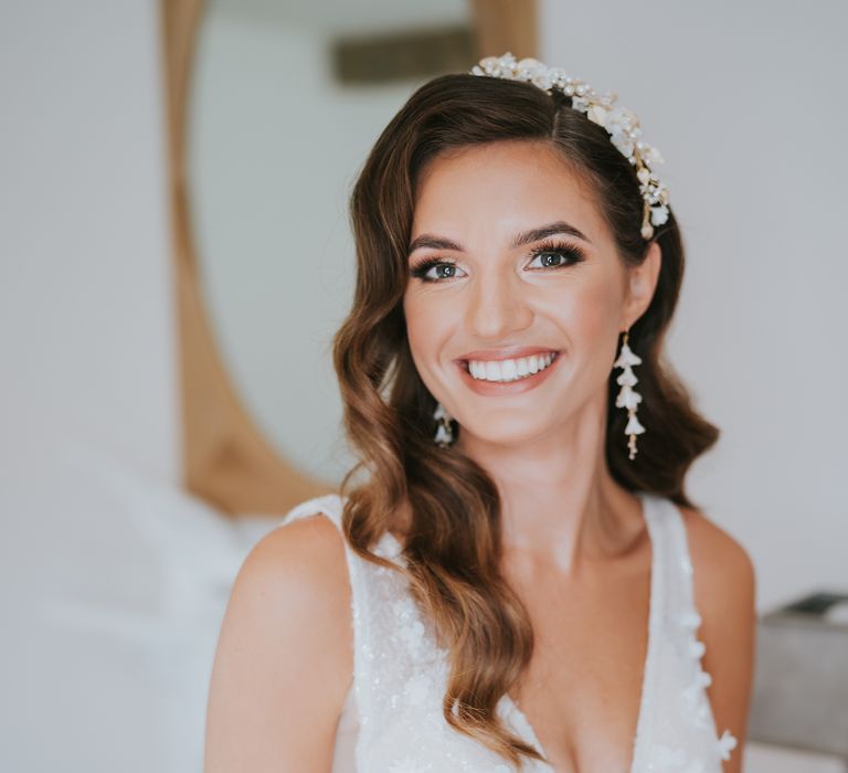 Bride with long flower earrings and flower and pearl headband accessory and plunging v-neck wedding dress