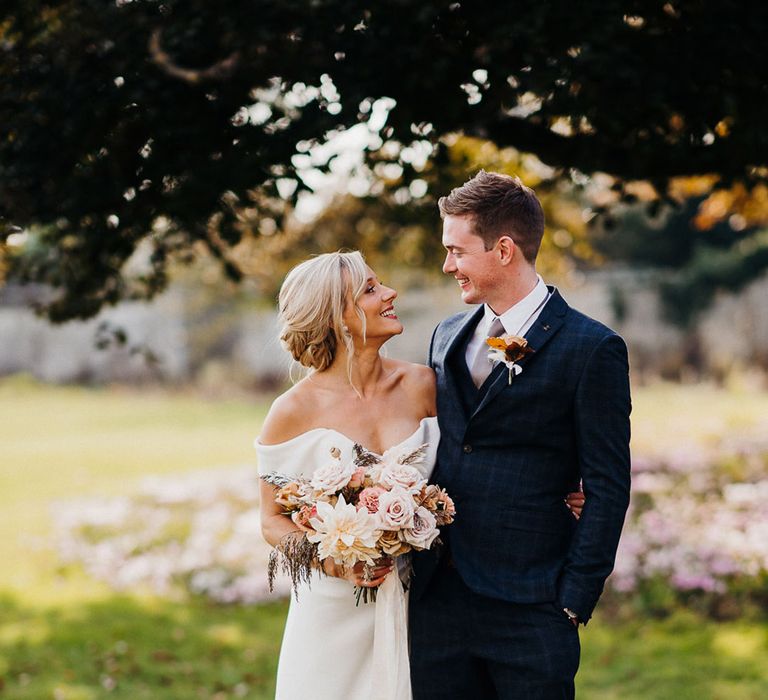 Bride and groom smile at each other at country house autumn wedding