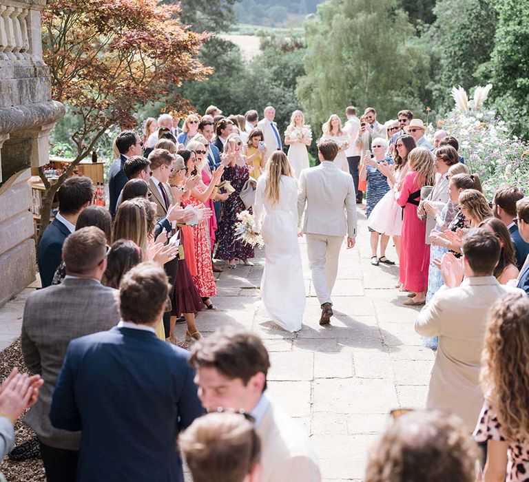 Bride and groom walk through their wedding guests at their outdoor wedding at Georgian home in Bath