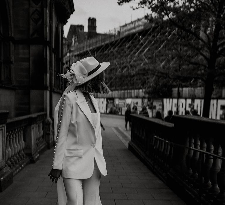 Bride in Nadine Merabi white pearl trouser wedding suit with fedora hat with veil attached for town hall wedding 