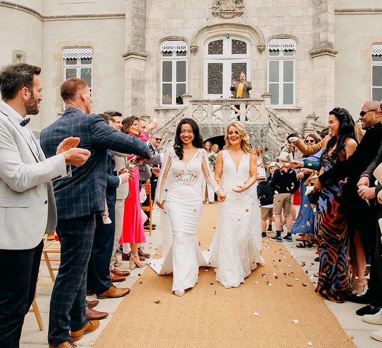 Brides walk back down the aisle as a married couple as wedding guests throw confetti 