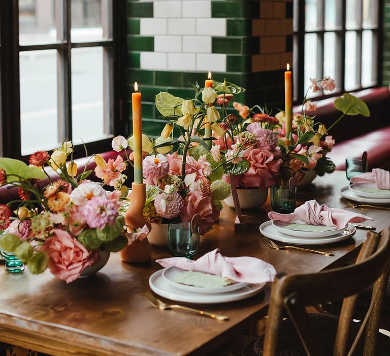 Wedding table decor at Singer Tavern with pink and green flower arrangements, ombre candles and gold cutlery 