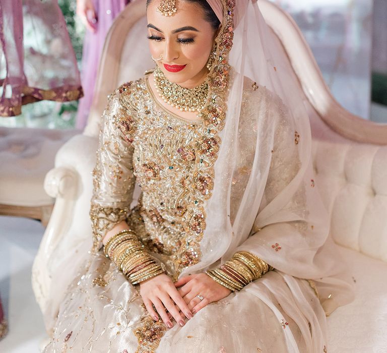 Embellished brightly coloured fabric is held above brides head on wedding day as she wears traditional saree for Walima & Nikkah