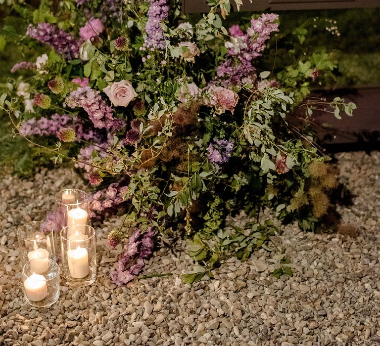 Purple florals beside wooden table outdoors complete with crystal glass 