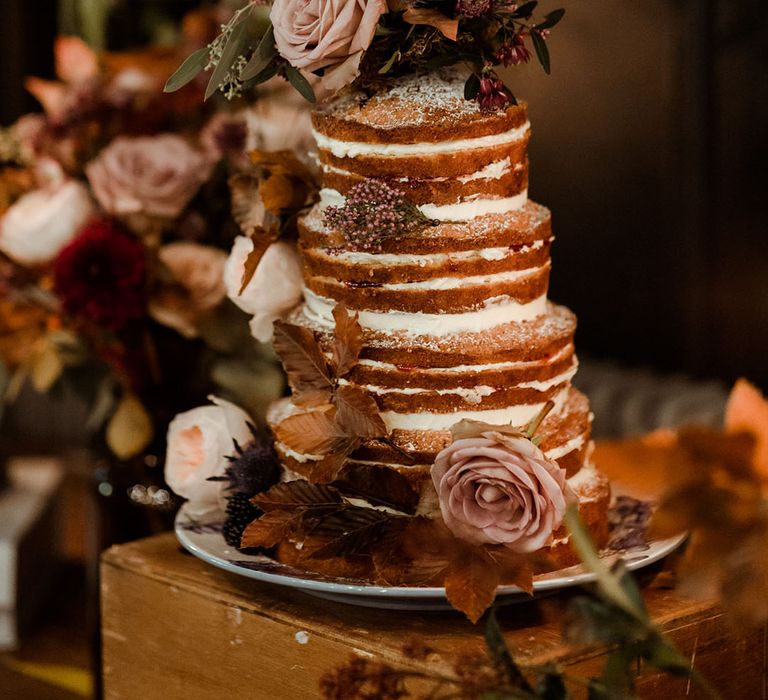 Rustic naked wedding cake complete with white frosting and real flower decor 