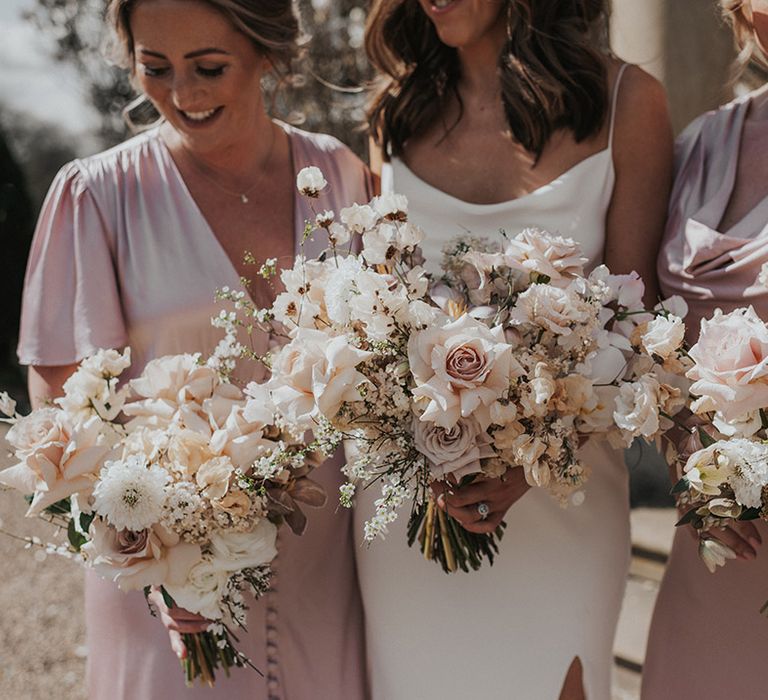 Bride with bridesmaids in pink dresses all holding matching pink and white flower bouquets 