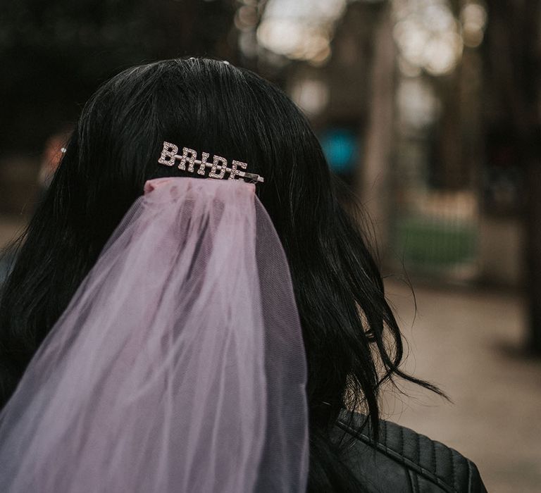 Bride wears 'Bride' hair clip in her back hair with pink wedding veil 