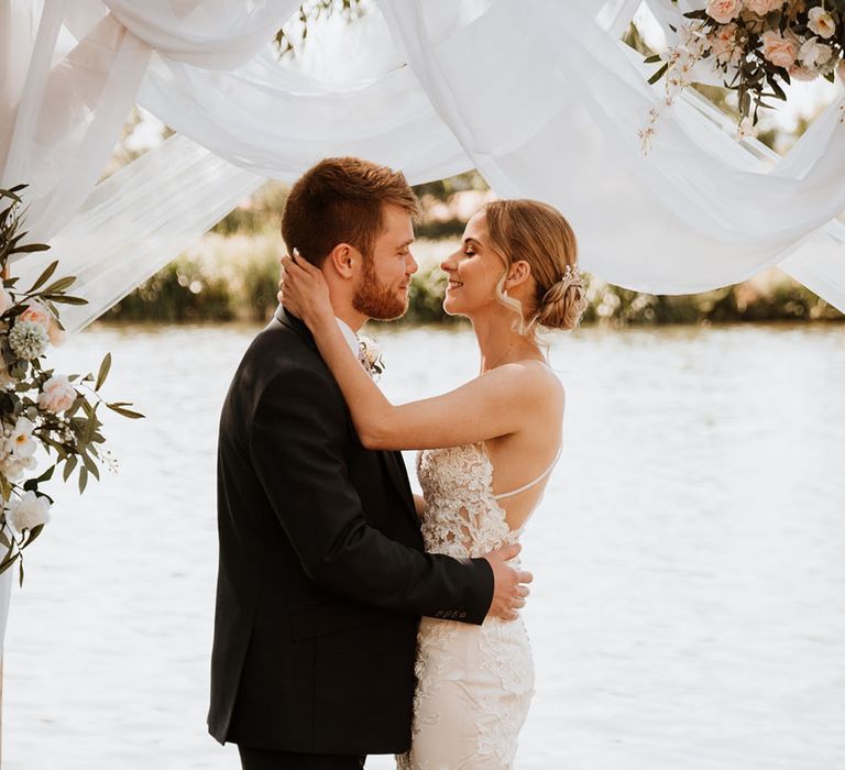 Bride wears her blonde hair in chignon bun complete with pearl hair accessories and wears Essense Of Australia lace wedding dress