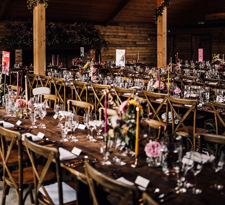 High Billinghurst Farm wedding venue with a chandelier, disco ball and foliage with pink and yellow taper candles decorating the tables 