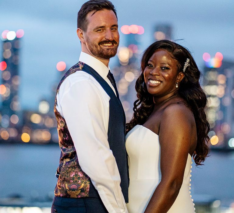 Groom wears white shirt and waistcoat as he stands beside his bride wearing Suzanne Neville wedding dress