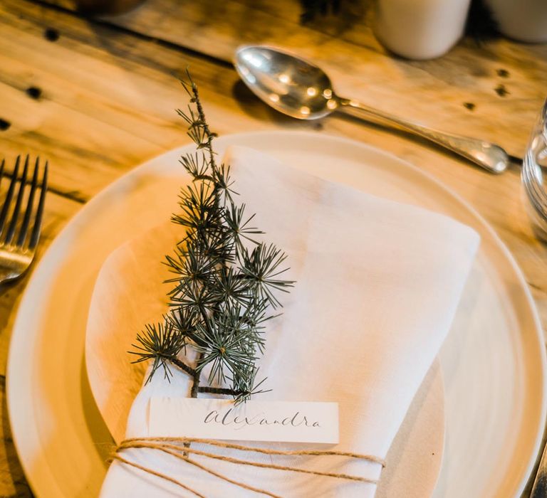 Simple and minimal white winter wedding table setting with a small sprig decorating the plates