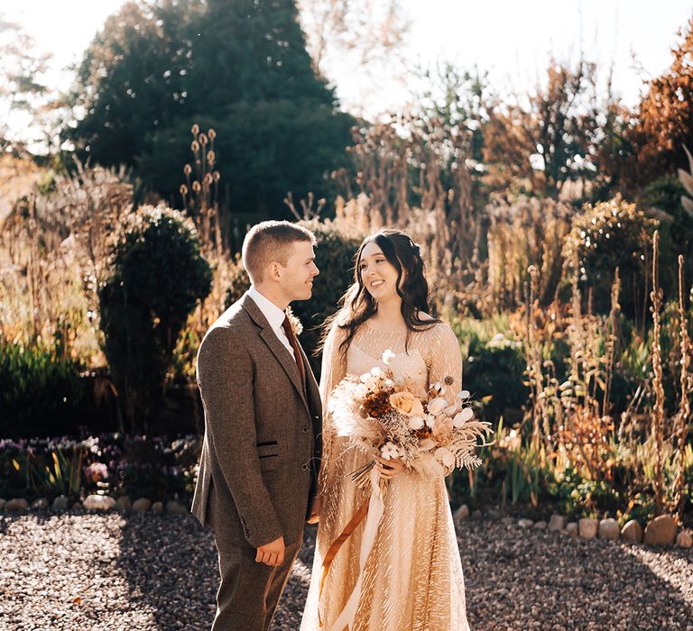 Bride & groom look lovingly at one another after boho and Autumnal styled wedding day at Lyde Court