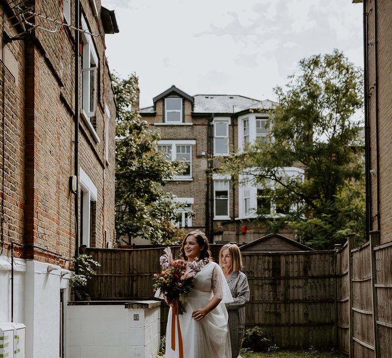 Bride walks with autumnal wedding bouquet in starry themed dress