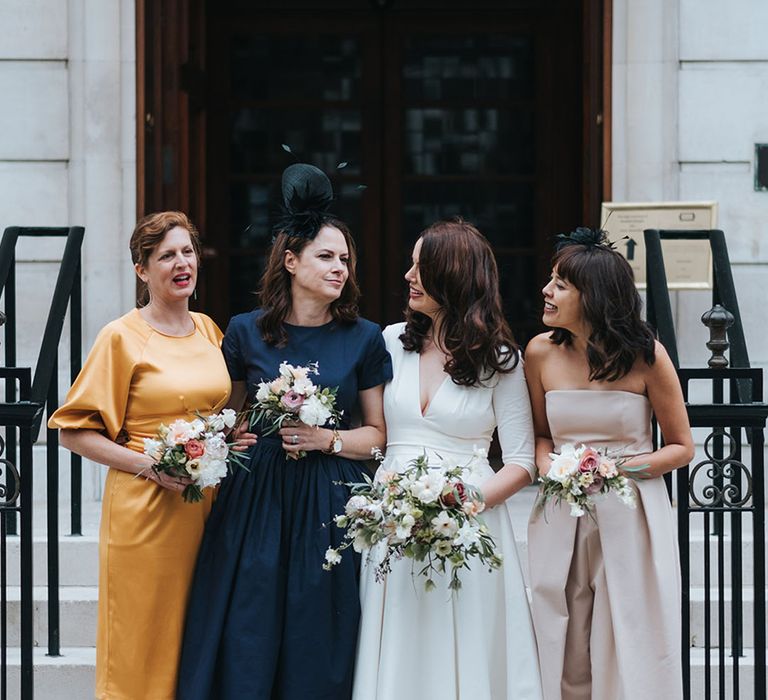 City town hall wedding with the bridesmaids in different coloured dresses posing with the bride 