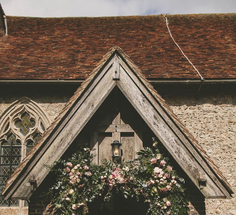 Pretty pink rose wedding flower arrangement decorating the entrance to the church 