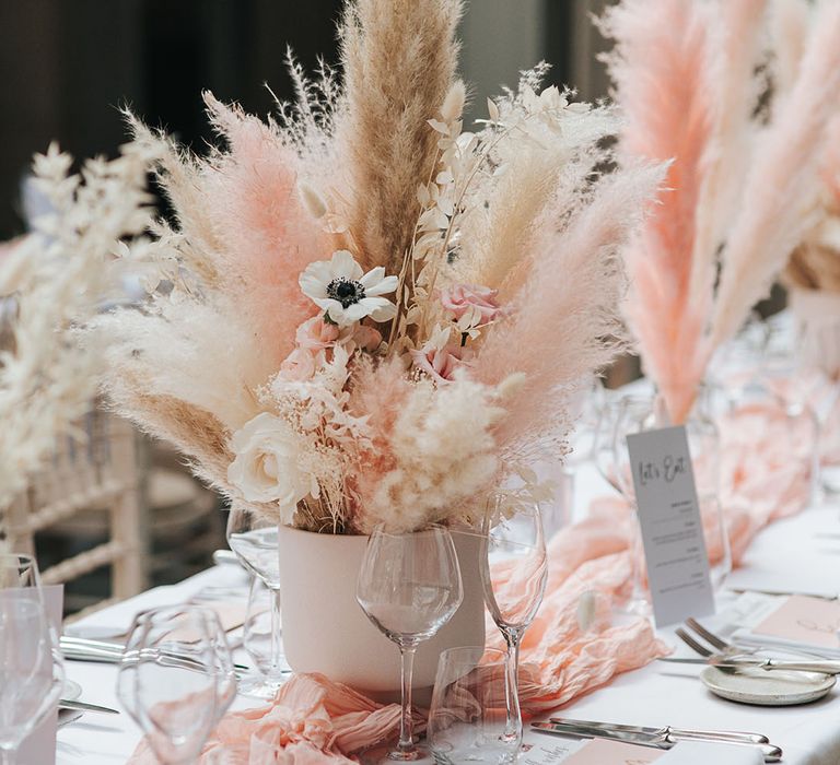 White poppy, pink and white roses and dried and dyed pampas grass centrepiece decorations on the table 