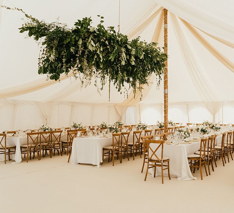 Hanging foliage installation above banquet tables complete with classic tablescape and gold cutlery 