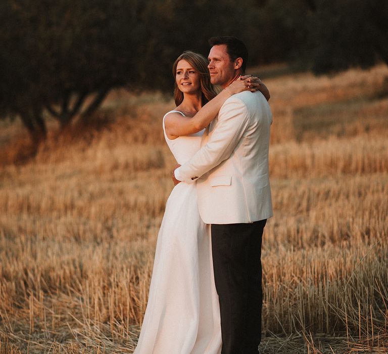 Bride in Suzanne Neville wedding dress embraces her groom during golden hour portraits