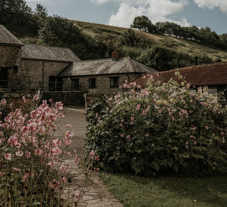 exterior of Westcott Barton wedding venue in Devon - British countryside with rolling hills and pink flowers 