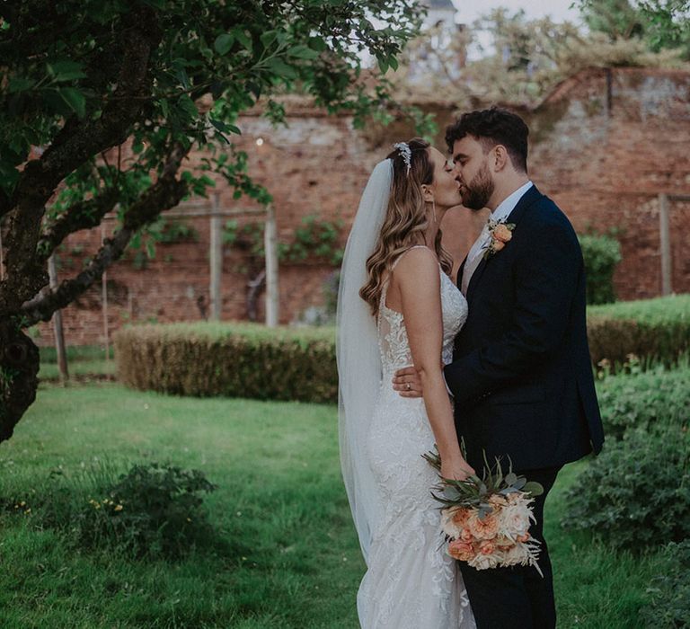 Cute couple portrait at Stanlake Park wedding with the bride in an embellished wedding dress and the groom in a navy suit jacket 