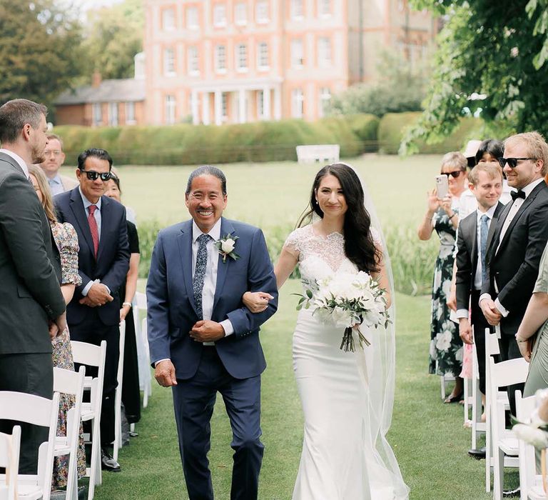 father of the bride walking his daughter down the aisle at outdoor wedding 