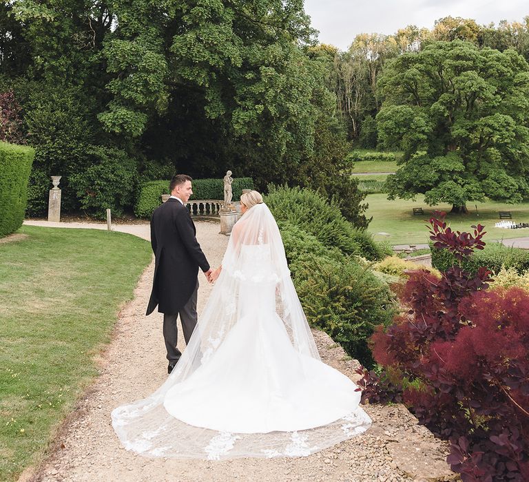 The bride and groom walk around the grounds of their classic and traditional country house wedding 