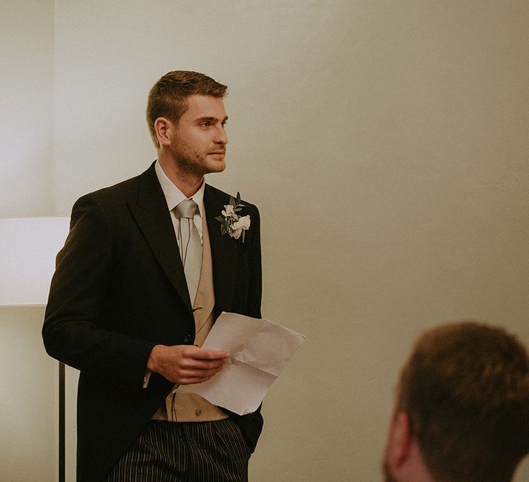 A groomsman stands and reads out his wedding speech at the wedding reception 