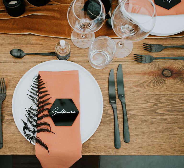 place setting with orange napkin and black hexagonal place setting 