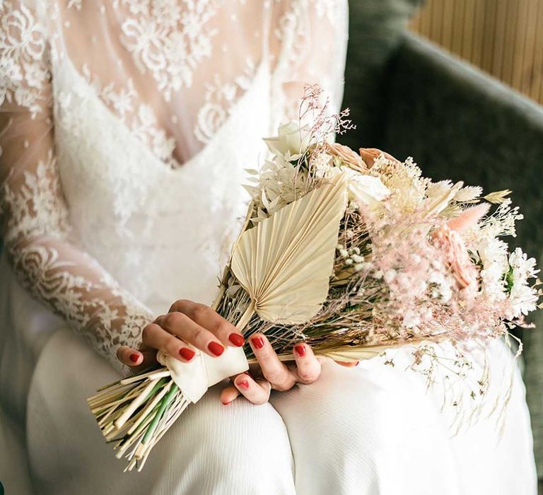 bride with red wedding nails holding a dried flower wedding bouquet 