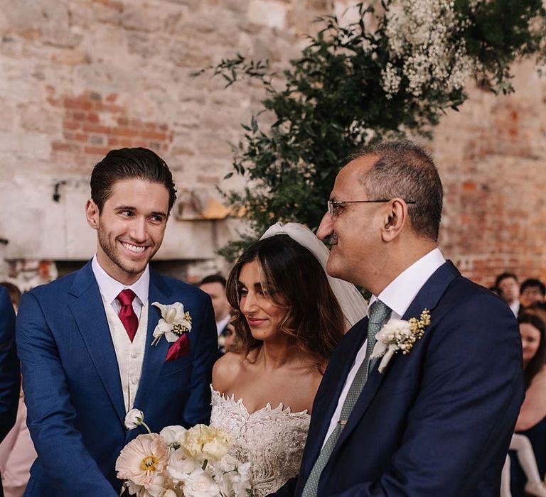 Father of the bride shakes the hand of the groom as they reach the end of the aisle 