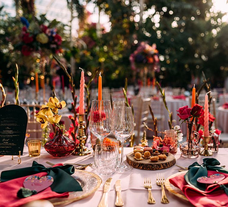 Pink and orange candles with bright pink place setting with dark green napkins and heart shaped place names 