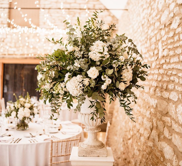 white flower and foliage wedding flower arrangements on a plinth