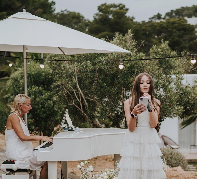 young bridesmaid in a white tulle skirt dress singing during alfresco reception at pure house ibiza