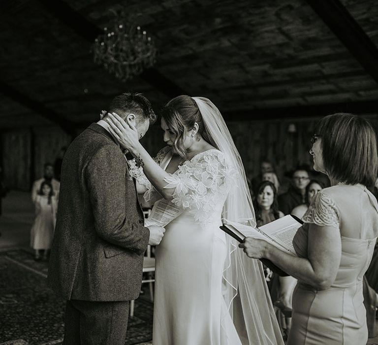 Bride wearing floral sleeve boho wedding dress embracing the groom at their wedding ceremony 