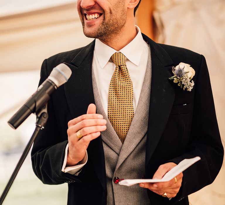 Groom in black morning suit with yellow tie and grey waistcoat 