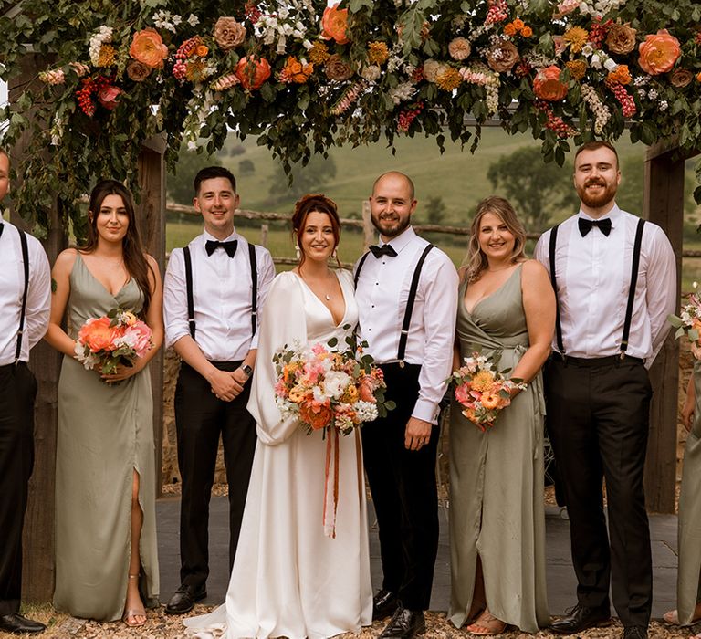 Green wrap bridesmaid dresses worn by the bridal party with the groom and groomsmen in black bow ties and suspenders 