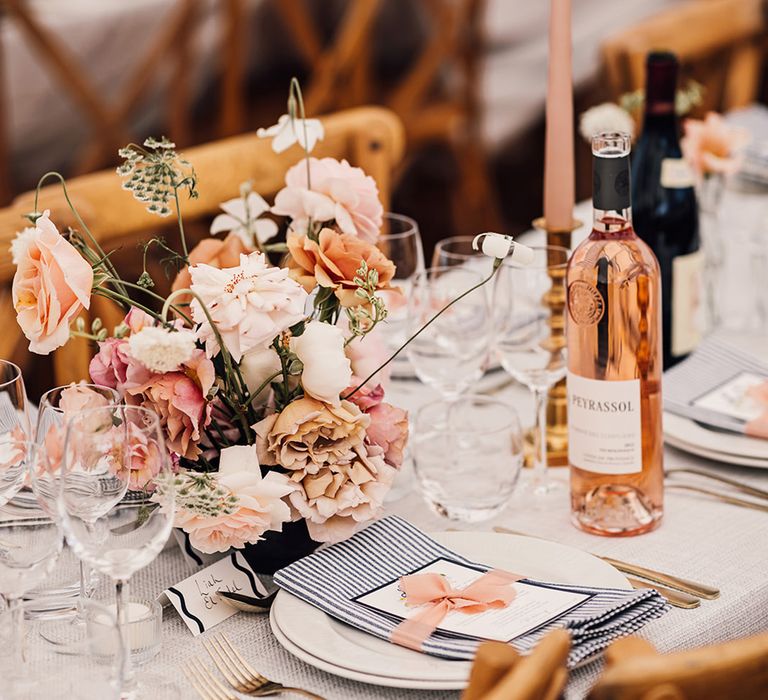 elegant pink and navy place setting decoration with flowers, taper candles and stripy napkin 