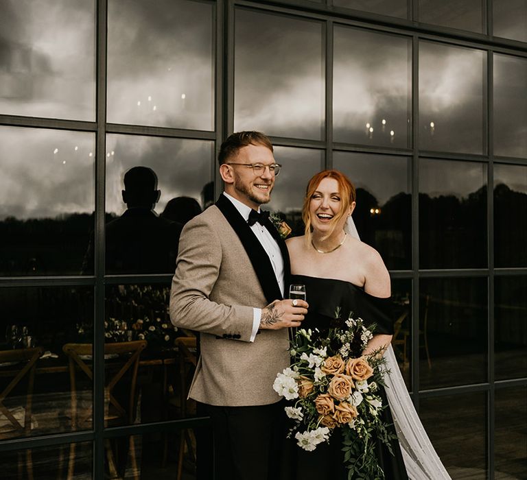 Bride in modern black wedding dress with off the shoulder detail with groom in neural wedding tuxedo 