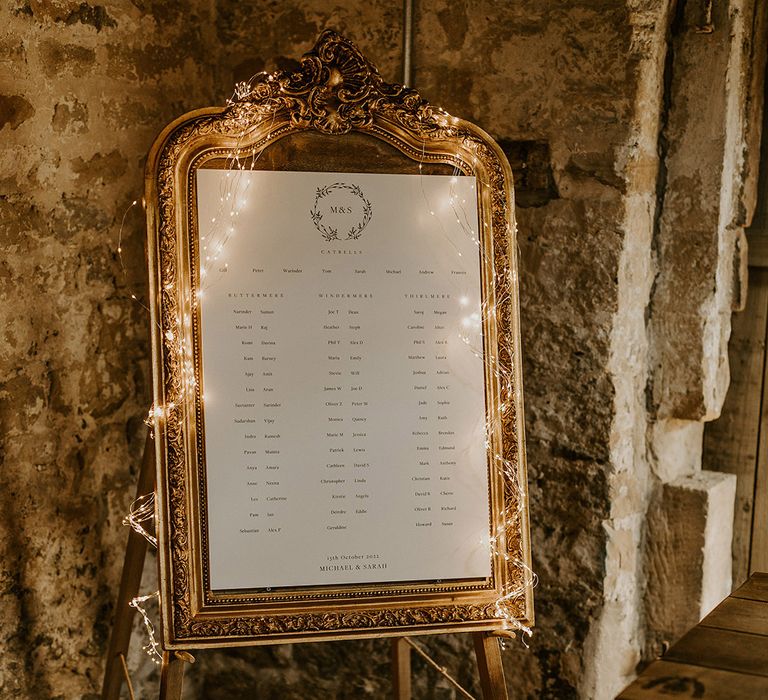 Gold wedding table plan decorated with fairy lights for cosy rustic barn wedding in Yorkshire countryside 