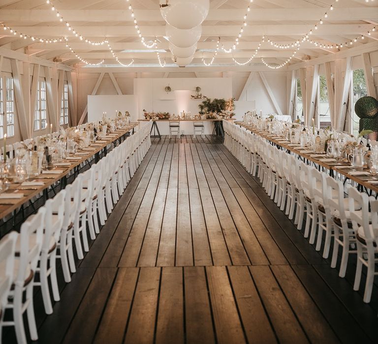 boho destination wedding reception with white chairs, pampas grass flowers and fairy lights 